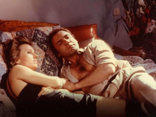 une femme et un homme habillé et couché sur un lit