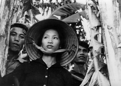 Une femme avec un chapeau vietnamien devant suivie de deux hommes